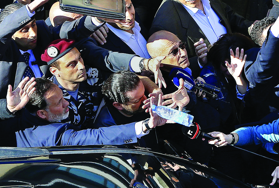 Bodyguards protect Lebanese Prime Minister Saad Hariri, center, from a water bottle thrown by demonstrators in downtown Beirut, Lebanon, Sunday, March 19, 2017. Demonstrators pelted the prime minister's car with water bottles on Sunday as protests against new taxes and a stagnant public wage scale gained force in the city. Hariri got out of his armored convoy behind the police line at the demonstration facing the government's capital building but could get no closer as protesters began throwing water bottles and shouting "Thieves!" (AP Photo/Bilal Hussein)